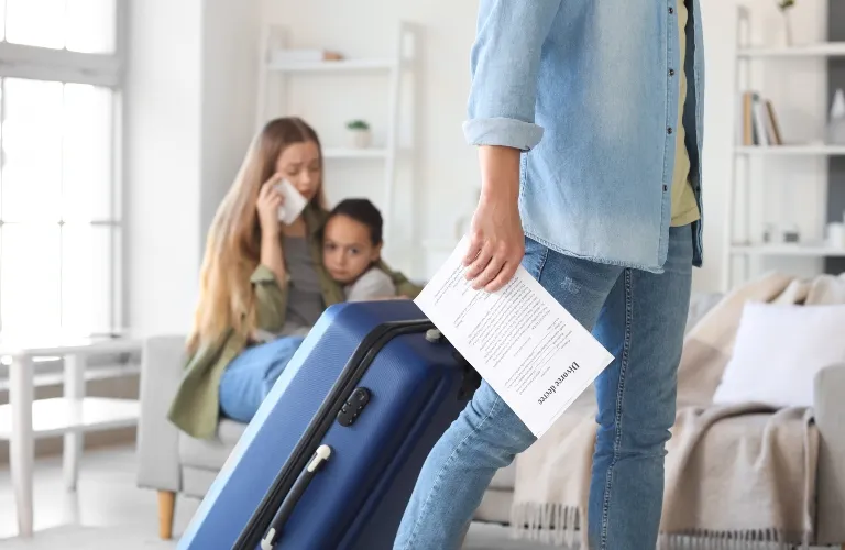 Person holding divorce papers and suitcase walking away, while woman and child sit distressed in background.