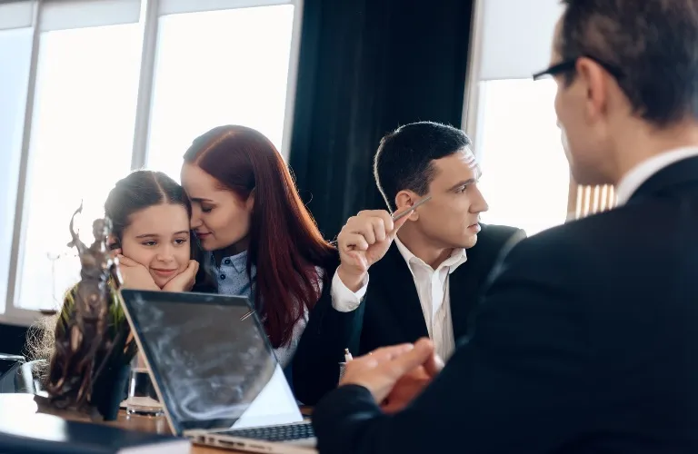 A family meeting with a lawyer, showing a mother comforting her daughter and two men in discussion.
