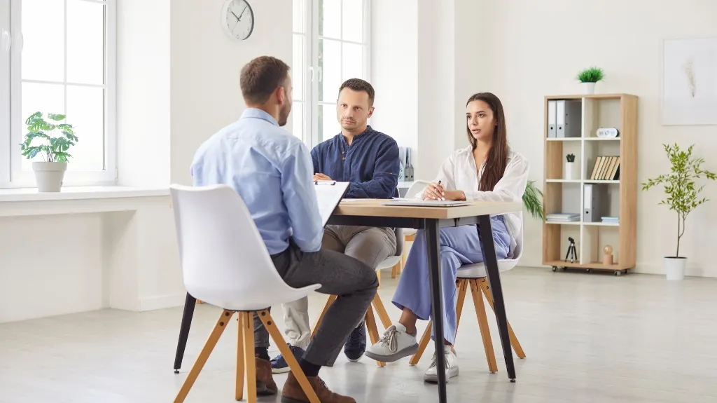 Three professionals engaged in a meeting in a bright, modern office space.