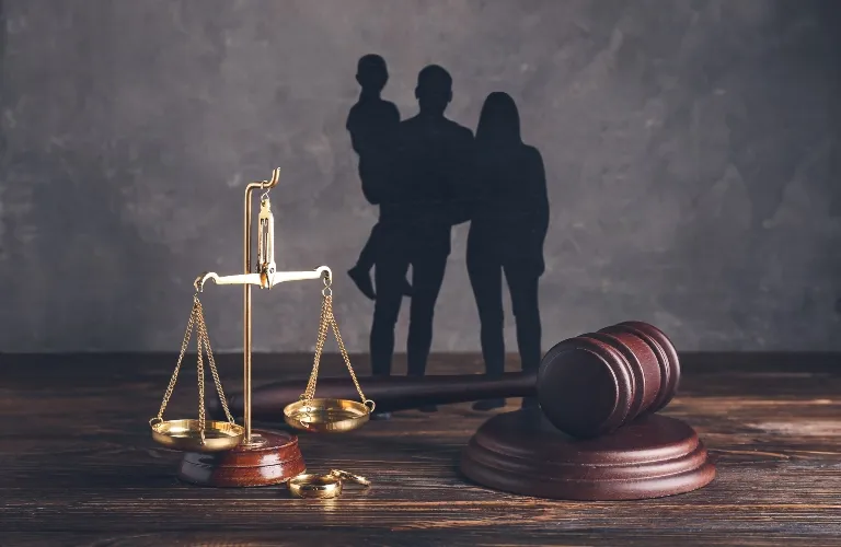 Scales of justice and wooden gavel on table with family silhouette background.